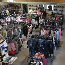 Overzicht van de winkelruimte met rekken vol kleding, boekenkasten en winkelmeubelen