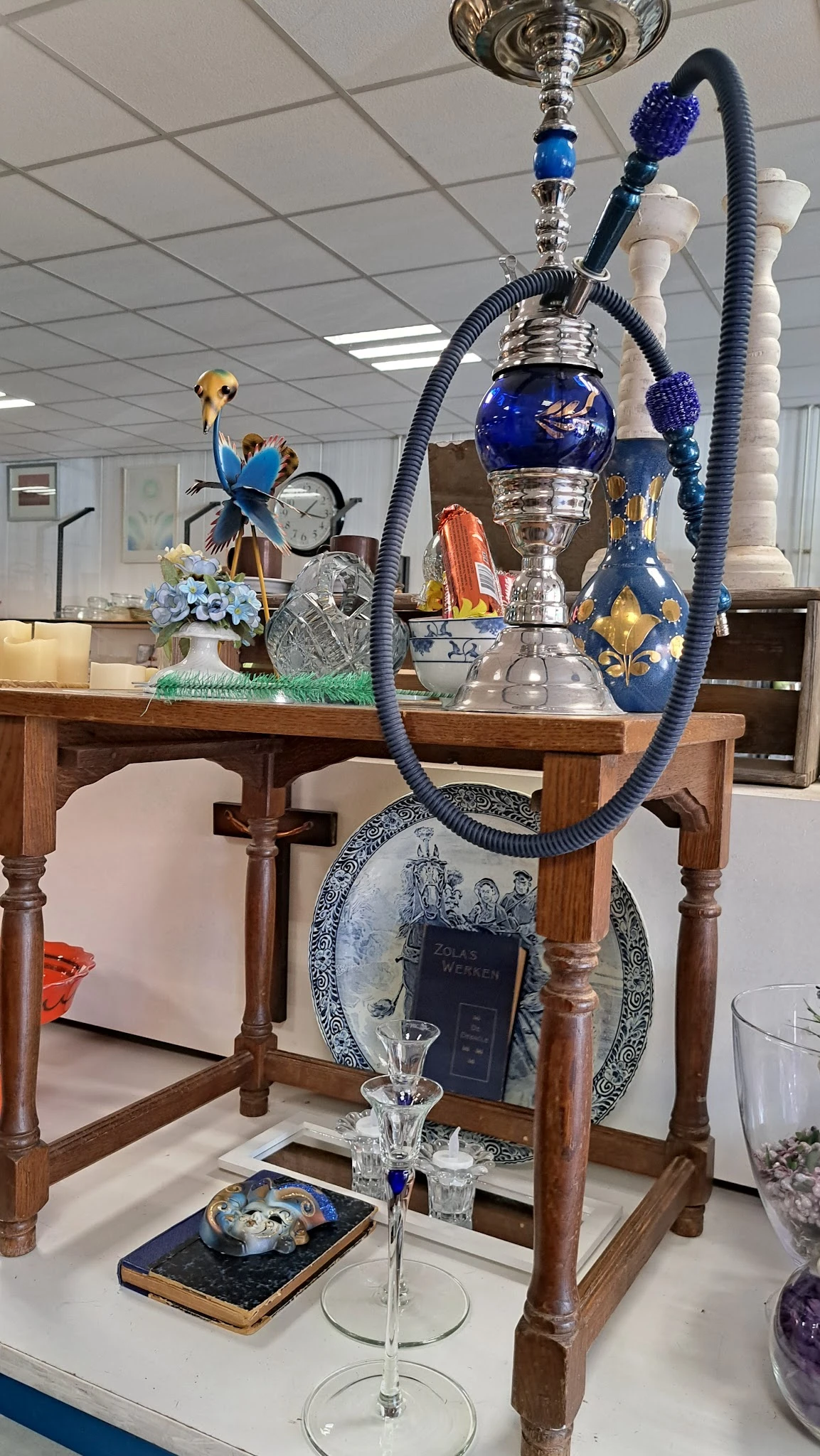 Houten tafel met diverse decoratieve artikelen zoals bloemen, trofeeën, borden en blauwe sierkandelaars