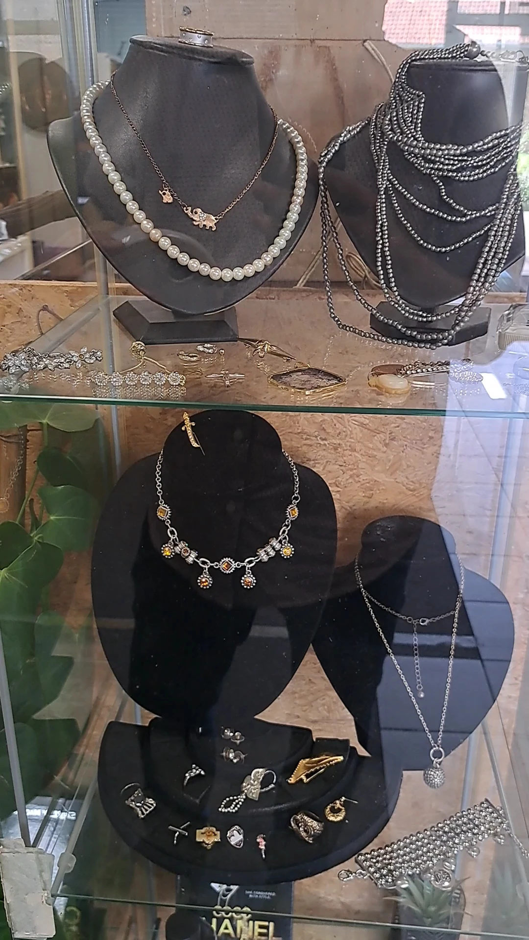 Uitgestalde sieraden in een vitrinekast: kettingen, armbanden en oorbellen op zwarte displays