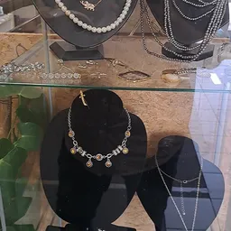 Uitgestalde sieraden in een vitrinekast: kettingen, armbanden en oorbellen op zwarte displays