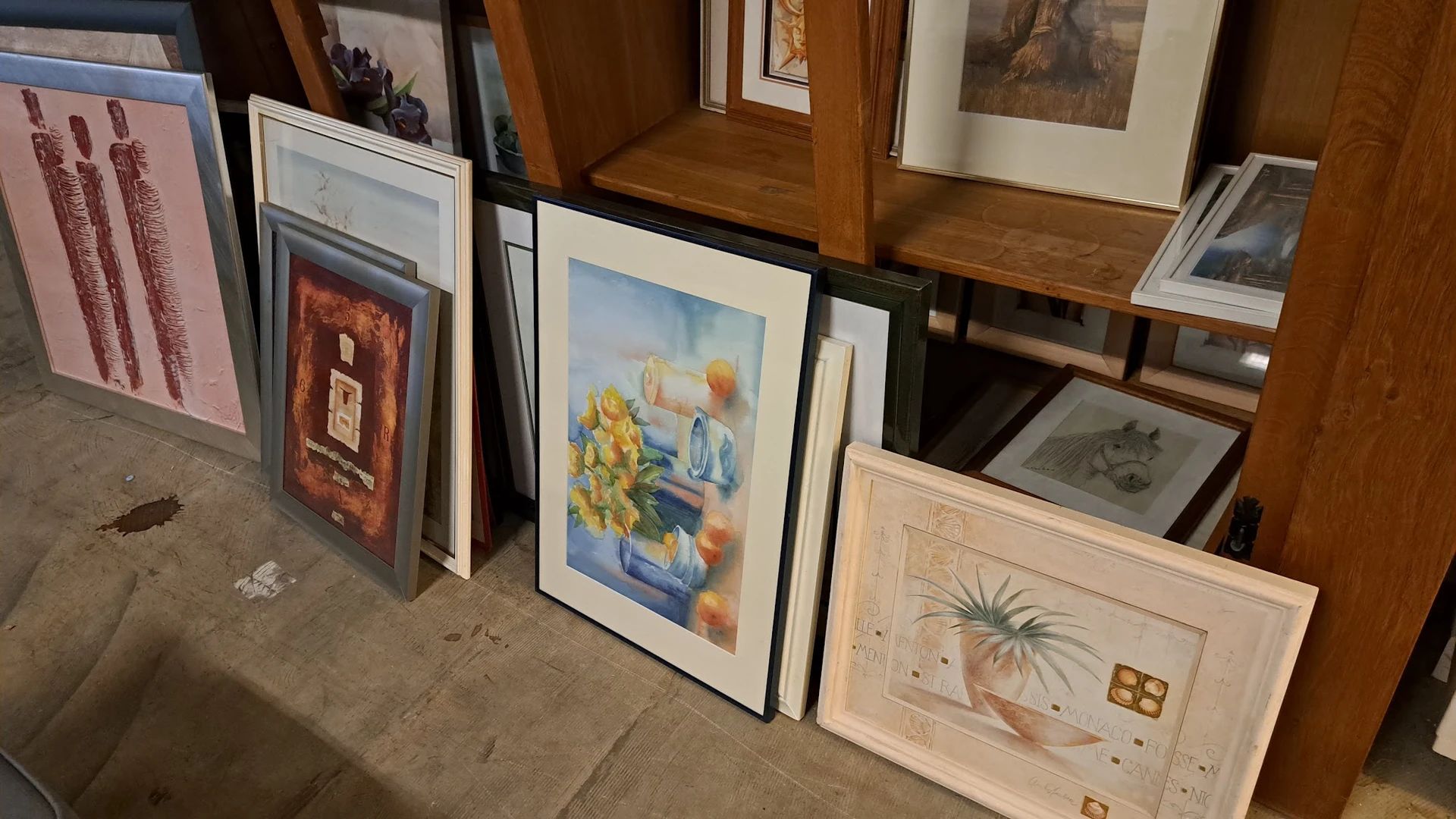 Ingelijste kunstwerken en schilderijen tegen elkaar in de winkel