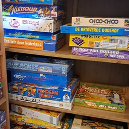 Stellage met stapels bordspellen en gezelschapsspellen, waaronder Choo-Choo, Wordstax en Moggenjacht