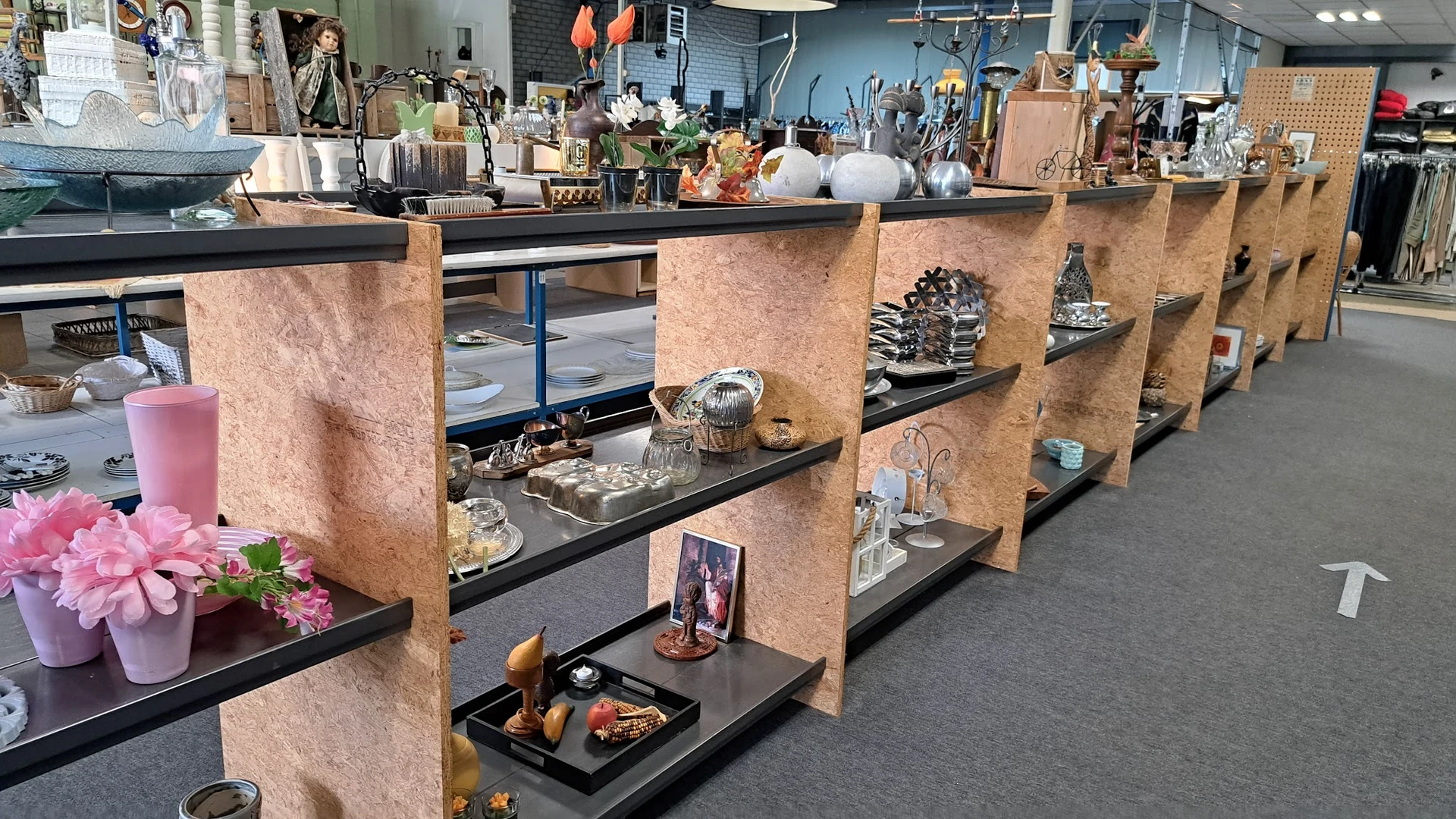Vitrinekast met decoratieve items, beeldjes, kandelaars en huisraad op zwarte planken met houten scheidingswanden