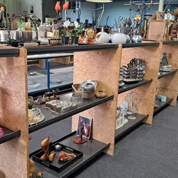 Vitrinekast met decoratieve items, beeldjes, kandelaars en huisraad op zwarte planken met houten scheidingswanden
