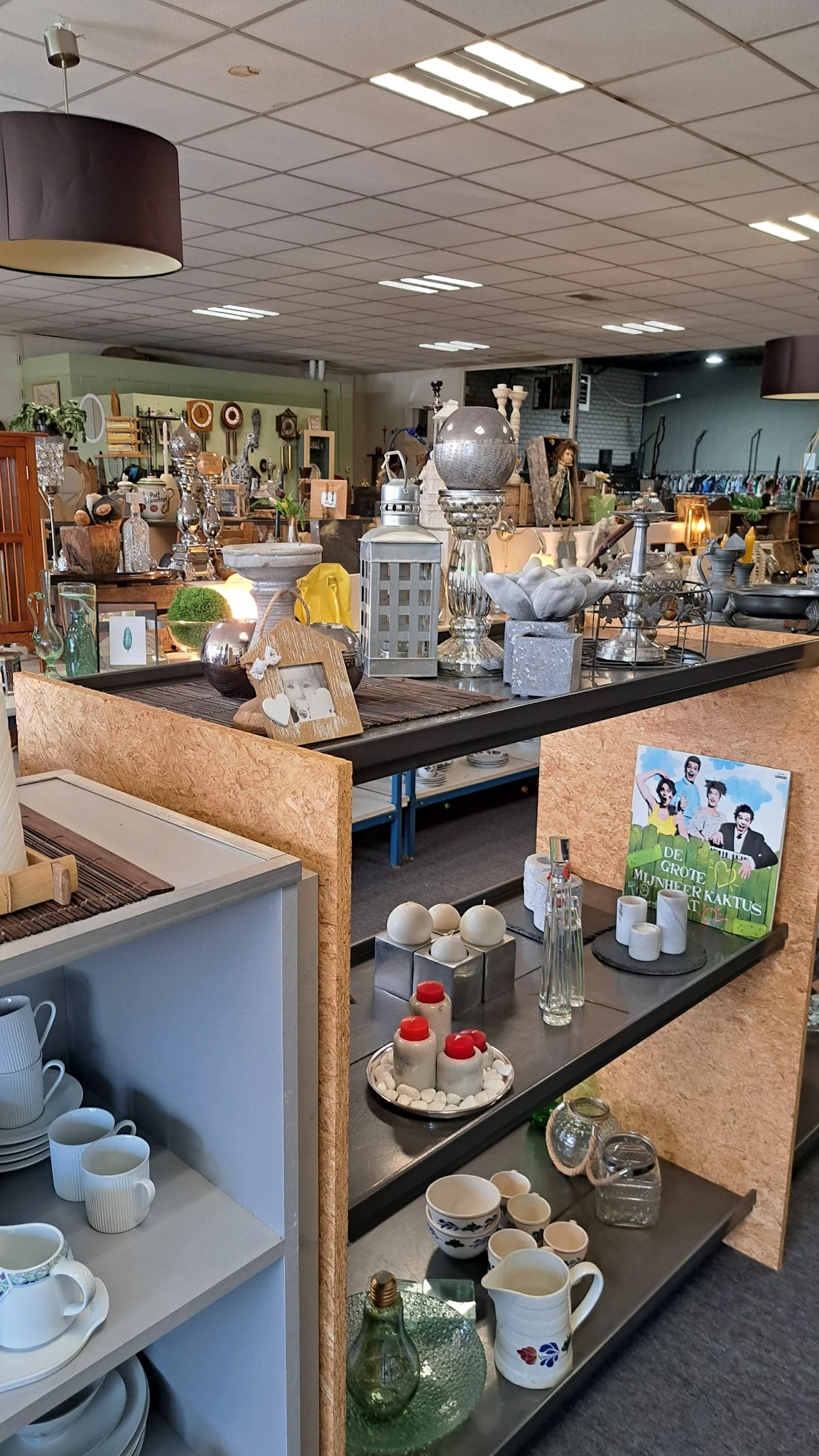 Winkelvloer met uitgestalde decoratieartikelen, vazen, lampen en huishoudelijke spullen op tafels en stellingen