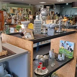 Winkelvloer met uitgestalde decoratieartikelen, vazen, lampen en huishoudelijke spullen op tafels en stellingen