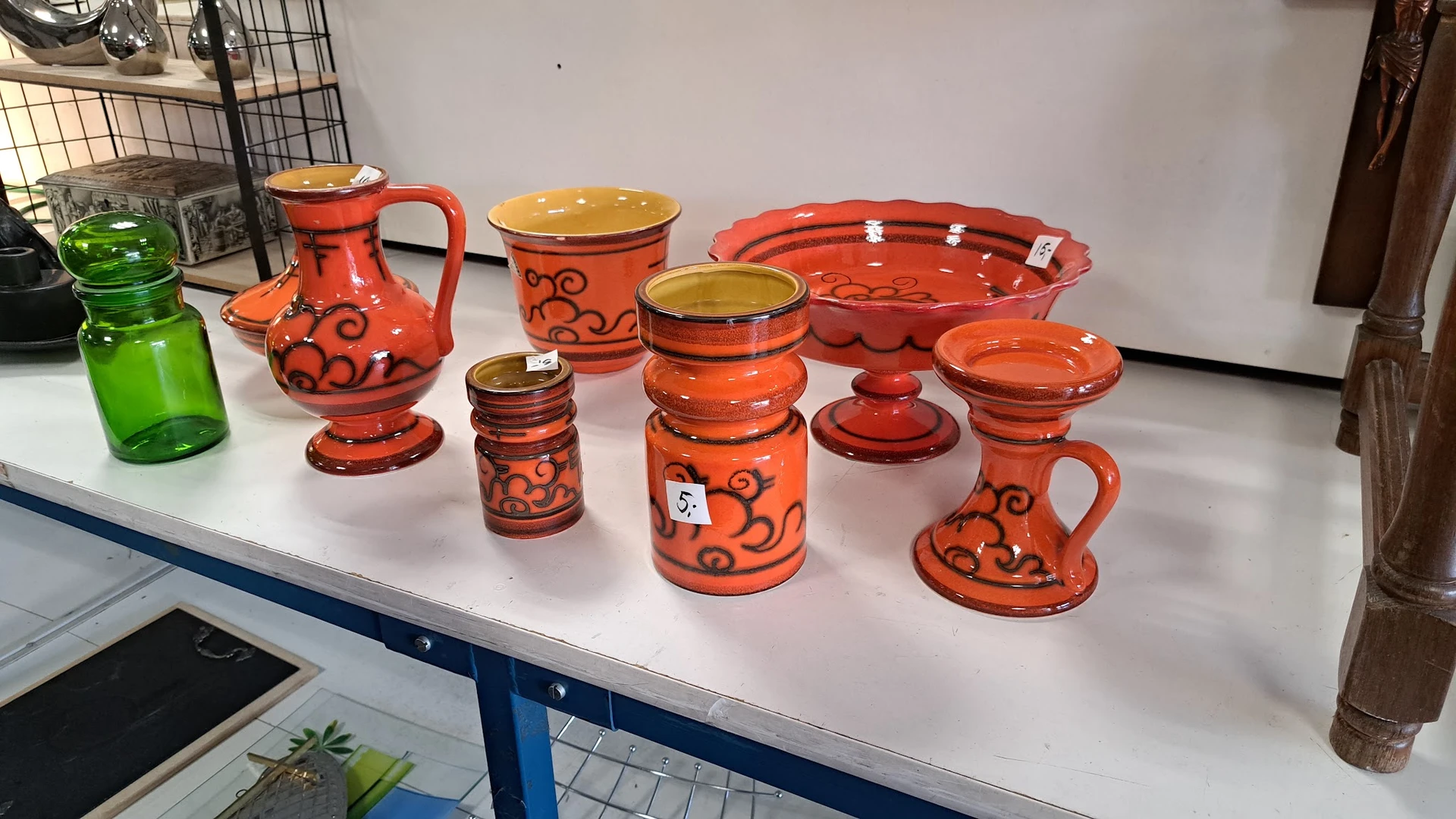 Uitgestalde rode en oranje serviesgoed met decoratieve patronen op een witte tafel