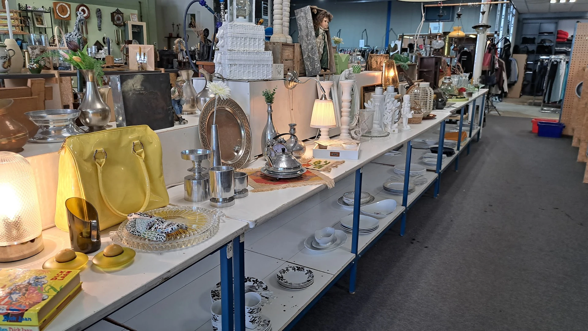 Lange toonbank met diverse huisraad en decoratie: lampen, servies, tassen, vazen en andere voorwerpen