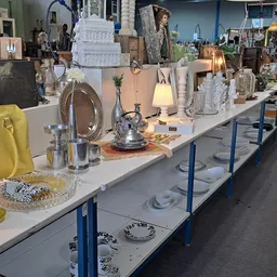 Lange toonbank met diverse huisraad en decoratie: lampen, servies, tassen, vazen en andere voorwerpen