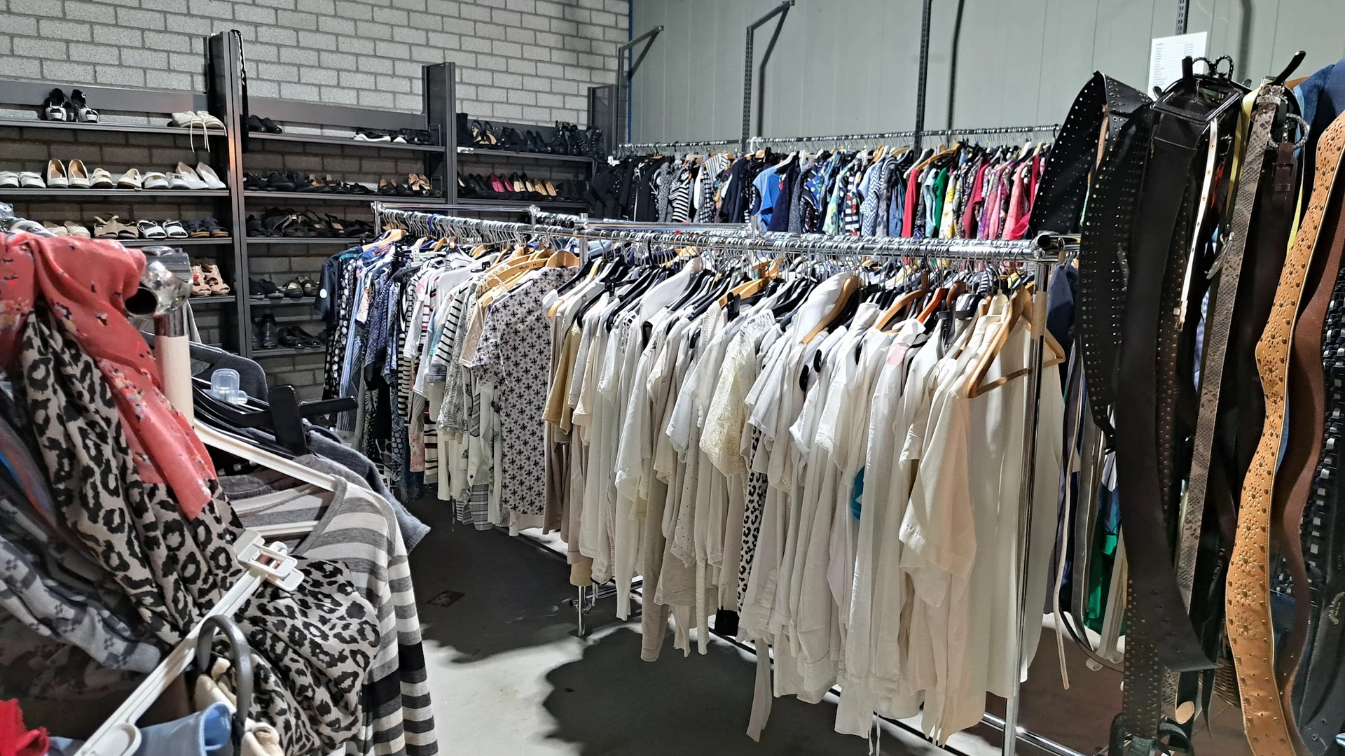 Rekken met uitgestalde tweedehands kleding in verschillende kleuren en stijlen