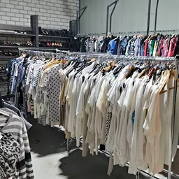 Rekken met uitgestalde tweedehands kleding in verschillende kleuren en stijlen