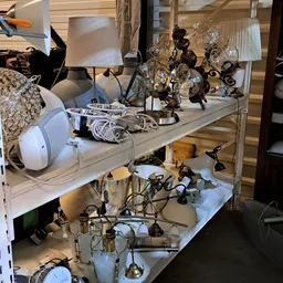 Twee stellingen met diverse tweedehands lampen en verlichtingsartikelen met witte kabels