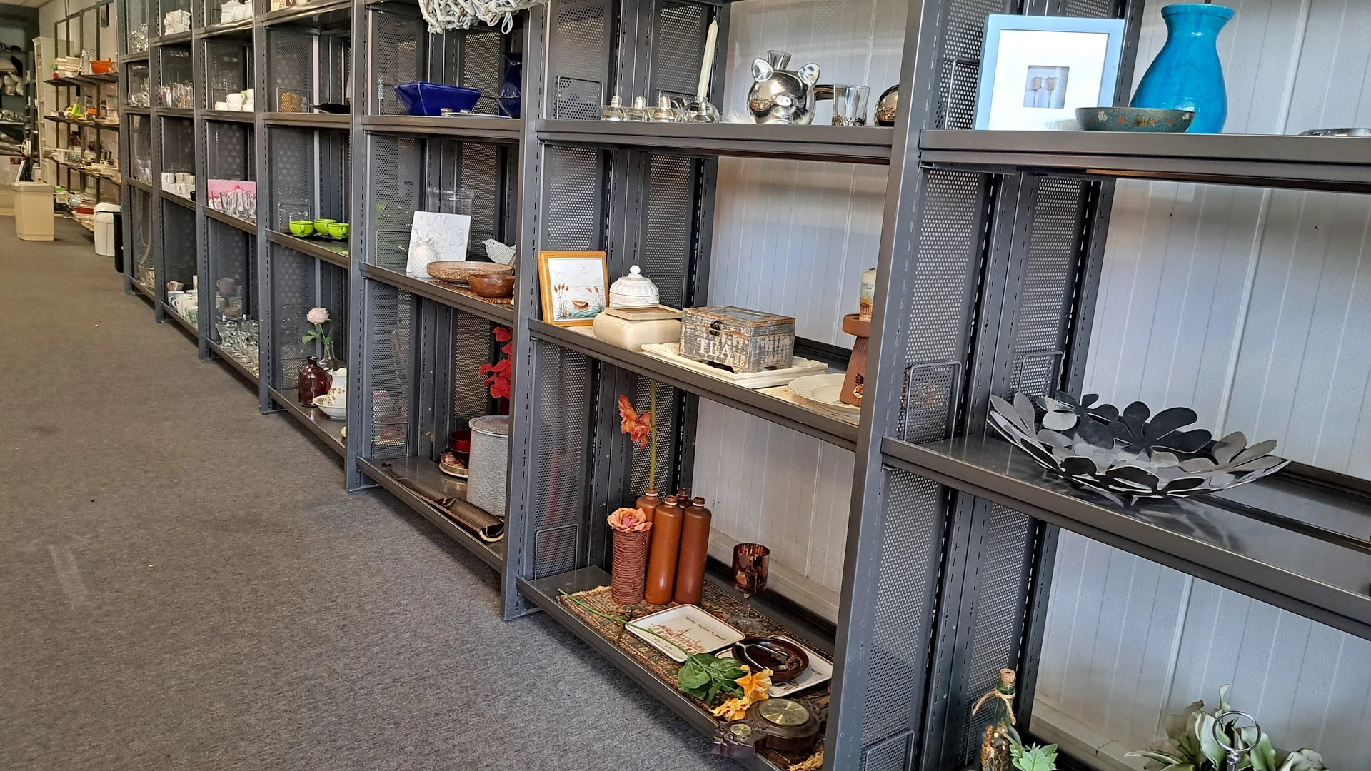 Vitrinekasten met uiteenlopend huishoudelijk en decoratief aanbod zoals serviesgoed, glazen, kaarsen en andere items