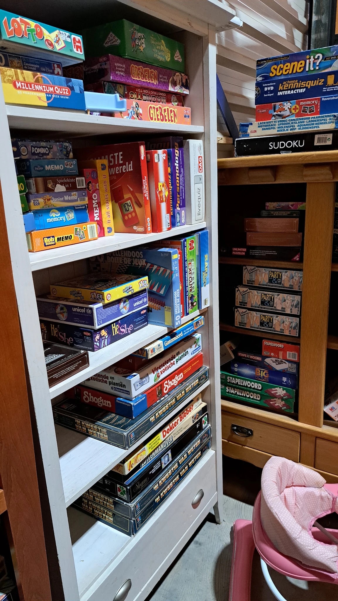 Boekenkasten met stapels bordspellen en dvd's netjes uitgestald op witte planken