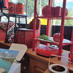 Winkelinterieur met rode meubels, rekken en diverse tweedehands spullen onder ramen