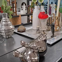 Vitrinekast met diverse decoratieve items: glazen vazen, zilveren beeldjes, vazen en rode stoffering