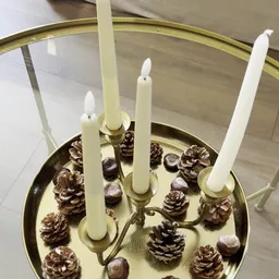 Decoratieve schaal met witte kaarsen in kandelaars en dennenappels als tafeldecoratie