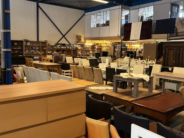 Winkelvloer met diverse meubels: tafels, stoelen en kasten uitgestald in de kringloopwinkel