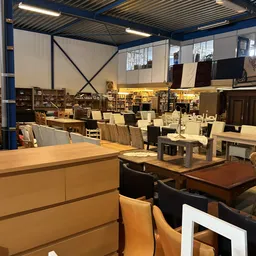 Winkelvloer met diverse meubels: tafels, stoelen en kasten uitgestald in de kringloopwinkel
