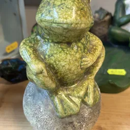 Close-up van een geel-groene stenen of keramieke beeldje met ronde vormen, mogelijk een decoratief object of kunstwerk
