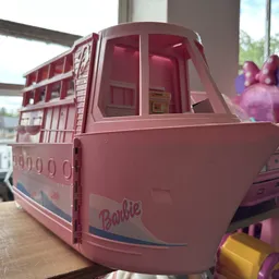 Roze Barbie-speelgoedbus op houten tafel bij raam met uitzicht op water