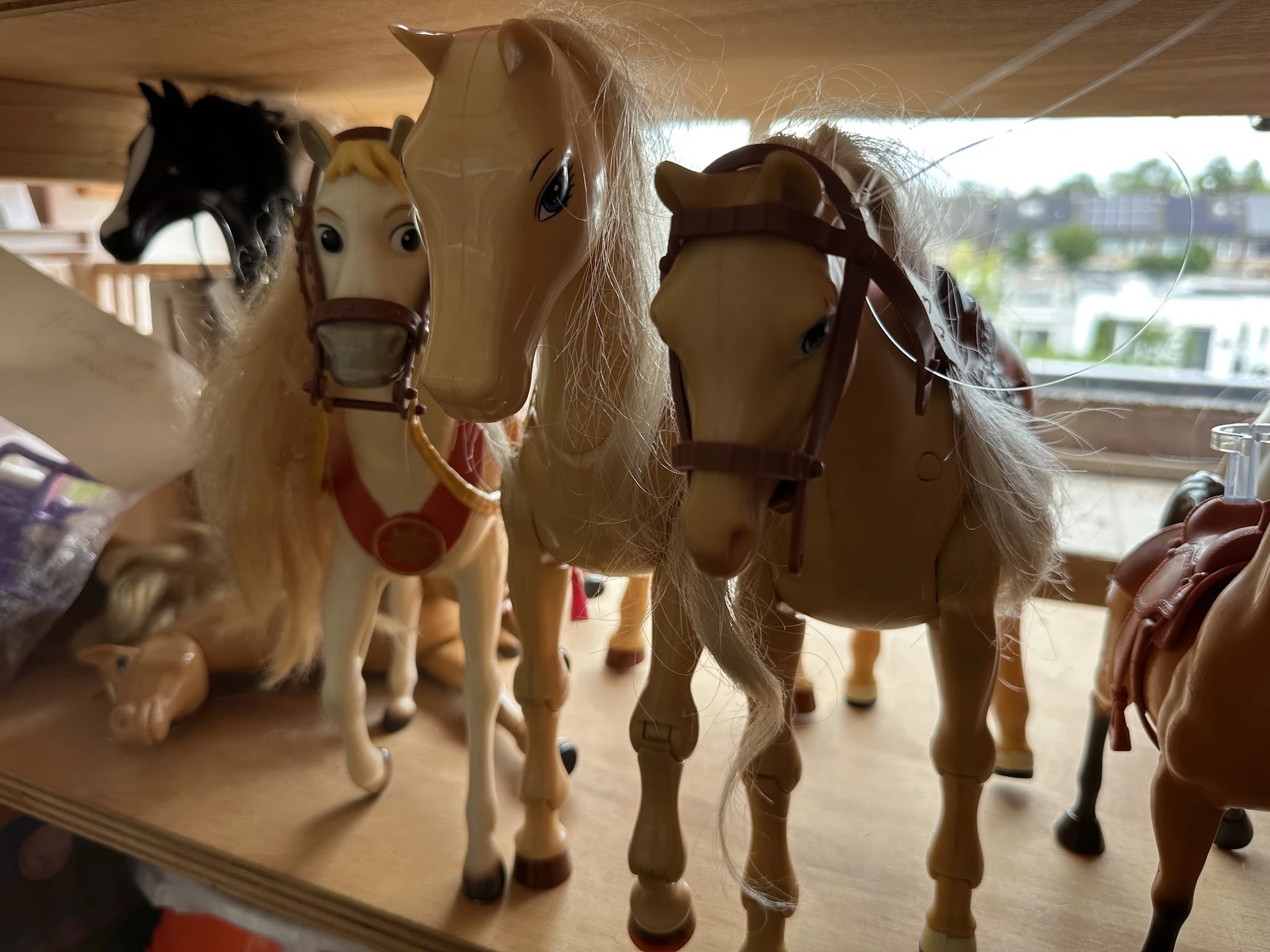 Vier decoratieve paardenbeeldjes met zadels en witte manen op een plank