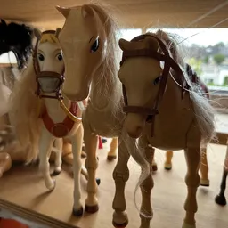 Vier decoratieve paardenbeeldjes met zadels en witte manen op een plank