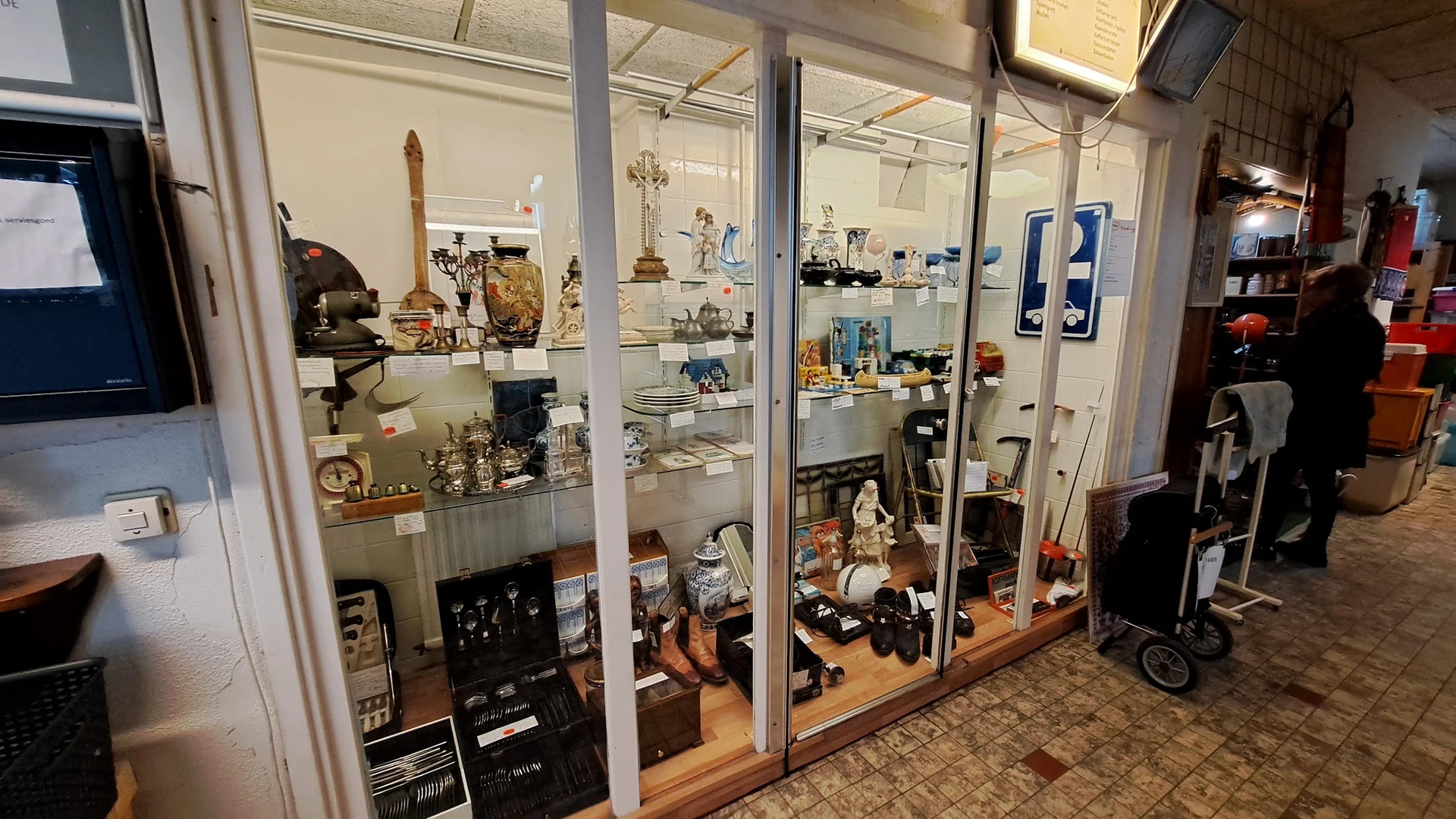 Glazen vitrinekasten met diverse tweedehands artikelen zoals servies, beeldjes, decoratie en huishoudspullen