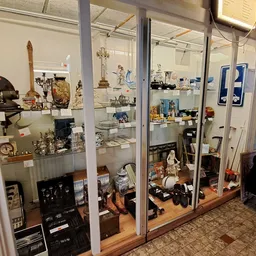 Glazen vitrinekasten met diverse tweedehands artikelen zoals servies, beeldjes, decoratie en huishoudspullen