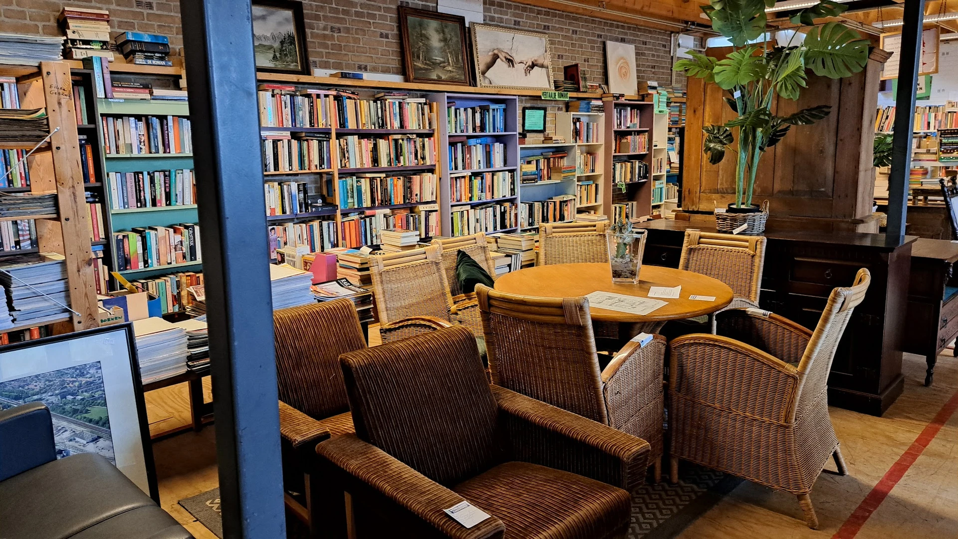Leesruimte met boekenkasten, rieten stoelen en houten tafel in kringloopwinkel