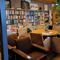 Leesruimte met boekenkasten, rieten stoelen en houten tafel in kringloopwinkel