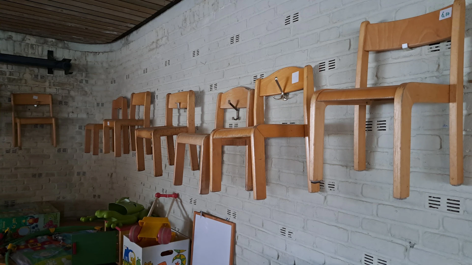 Houten stoelen en tafels opgehangen aan een witte bakstenen wand