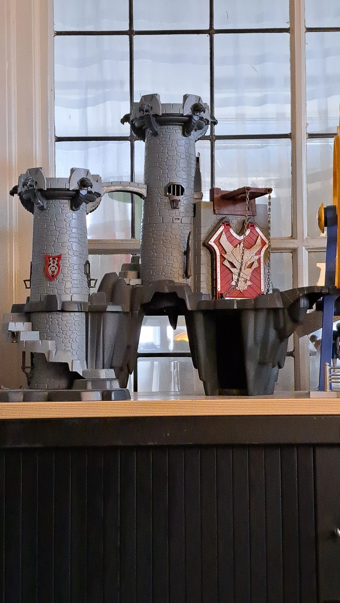 Decoratief kasteel van steen met torens, poppen en rood geverfde deurdetail op houten plank