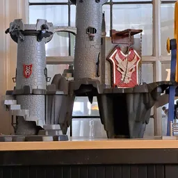 Decoratief kasteel van steen met torens, poppen en rood geverfde deurdetail op houten plank