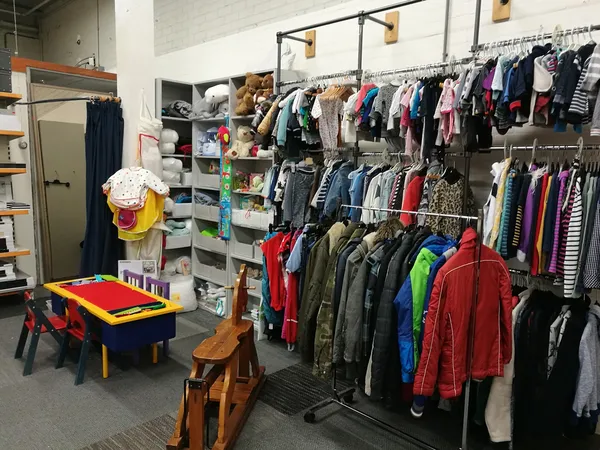 Winkelvloer met kledingrekken, stellingen met kinderkleding en speelhoek met tafel