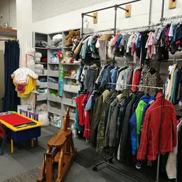Winkelvloer met kledingrekken, stellingen met kinderkleding en speelhoek met tafel