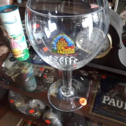 Glazen bierglas met Trappist-logo en merkopdruk op tafel