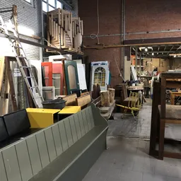 Winkelvloer met houten meubels, deuren, stellingen en diversen spullen in een ruime kringloopwinkel