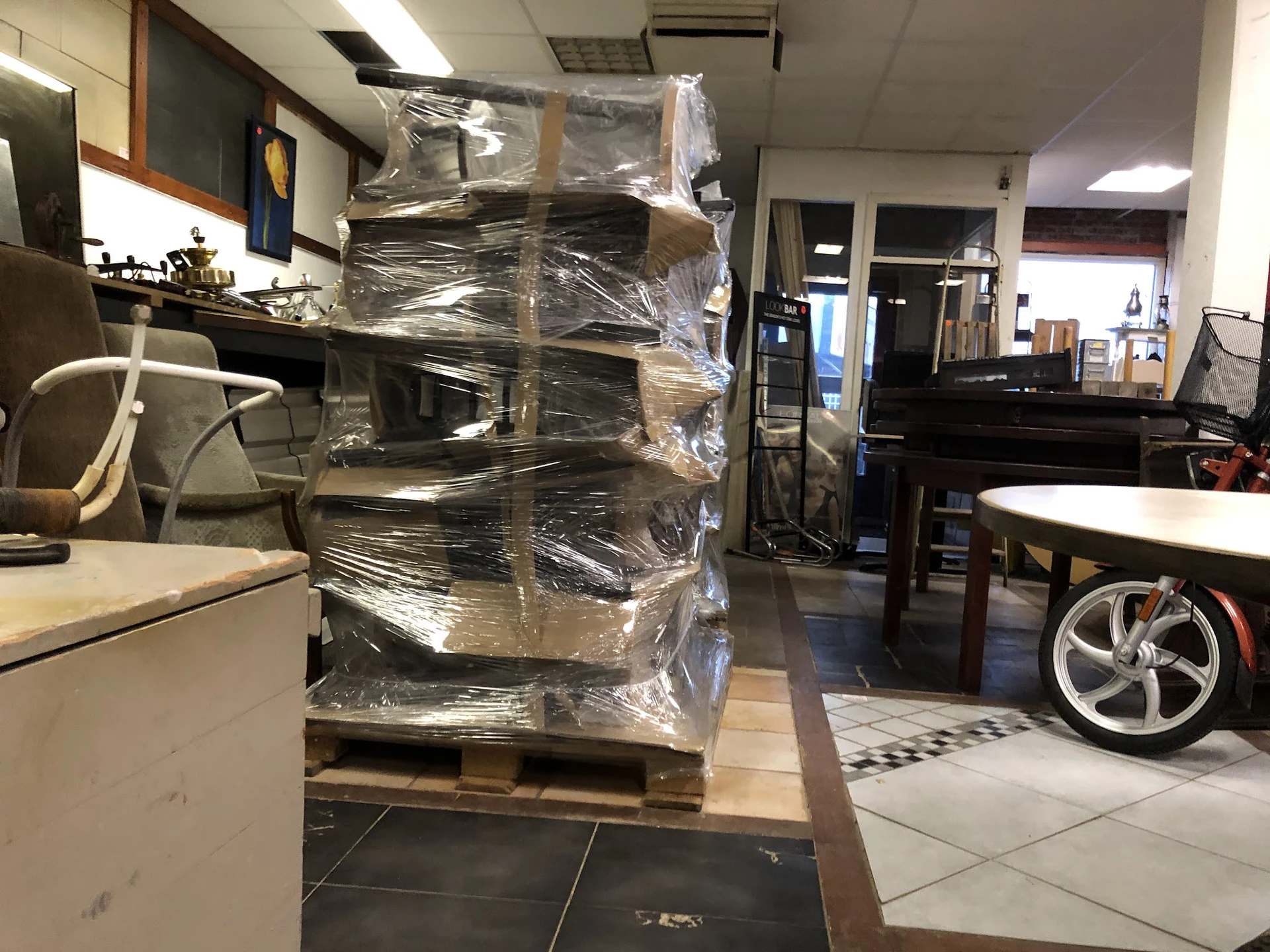 In plastic verpakte stapel meubels of huishoudartikelen op pallet in winkelruimte