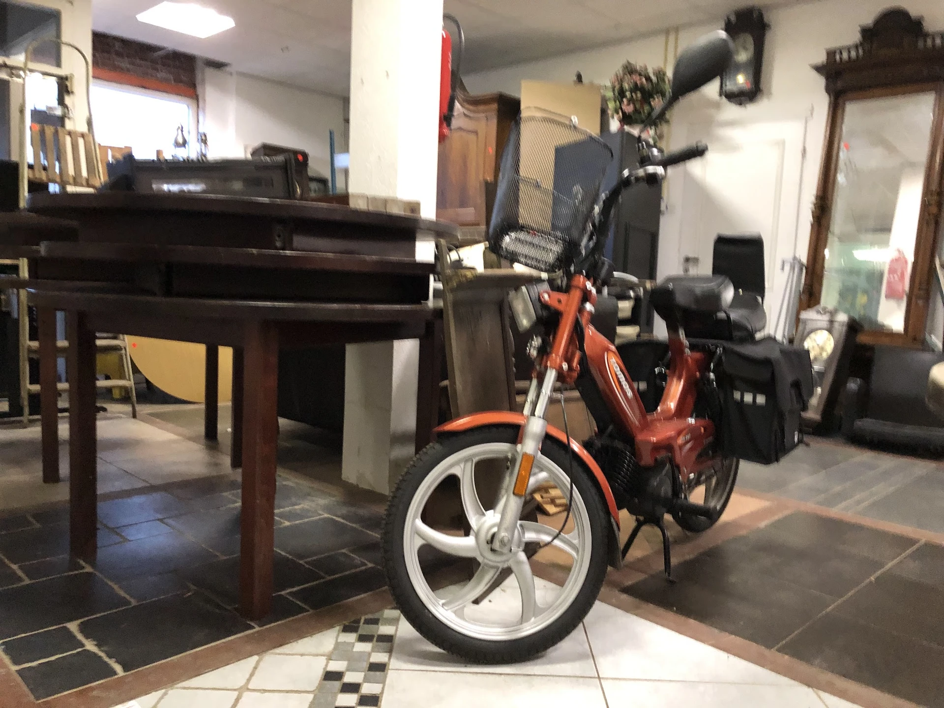 Rood-zwarte scooter of motorfiets met witte wielen in een winkelinterieur