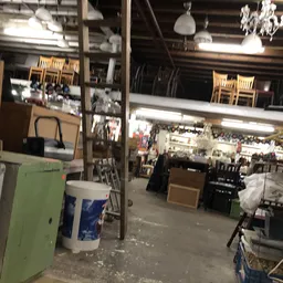 Winkelvloer met stellingen, dozen en diverse spullen in een kringloopwinkel