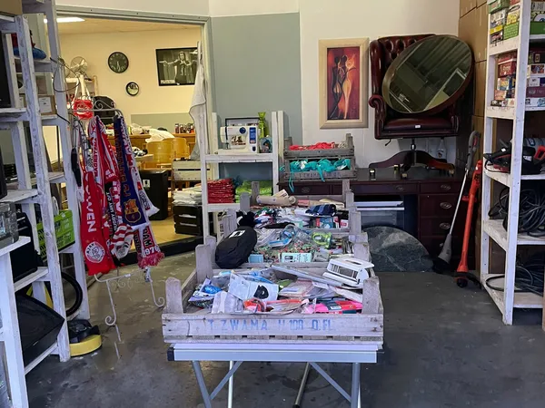 Kringloopwinkelinterieur met tafels vol spullen, stellingen, kleding en elektronische apparatuur