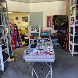 Kringloopwinkelinterieur met tafels vol spullen, stellingen, kleding en elektronische apparatuur