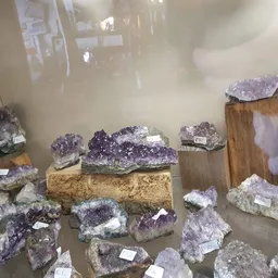 Uitgestalde amethist kristalclusters en geodes op houten blokken en in rekken
