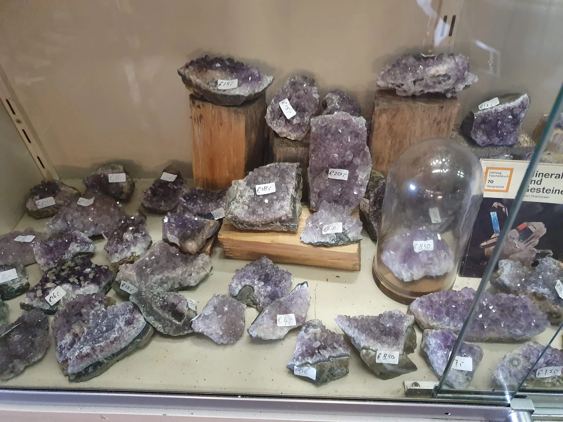 Uitstalling van amethist kristallen en geodes in verschillende maten op houten en zwarte ondergronden