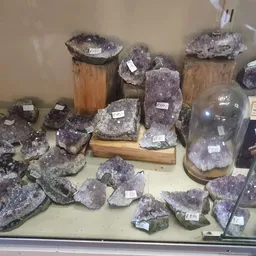 Uitstalling van amethist kristallen en geodes in verschillende maten op houten en zwarte ondergronden