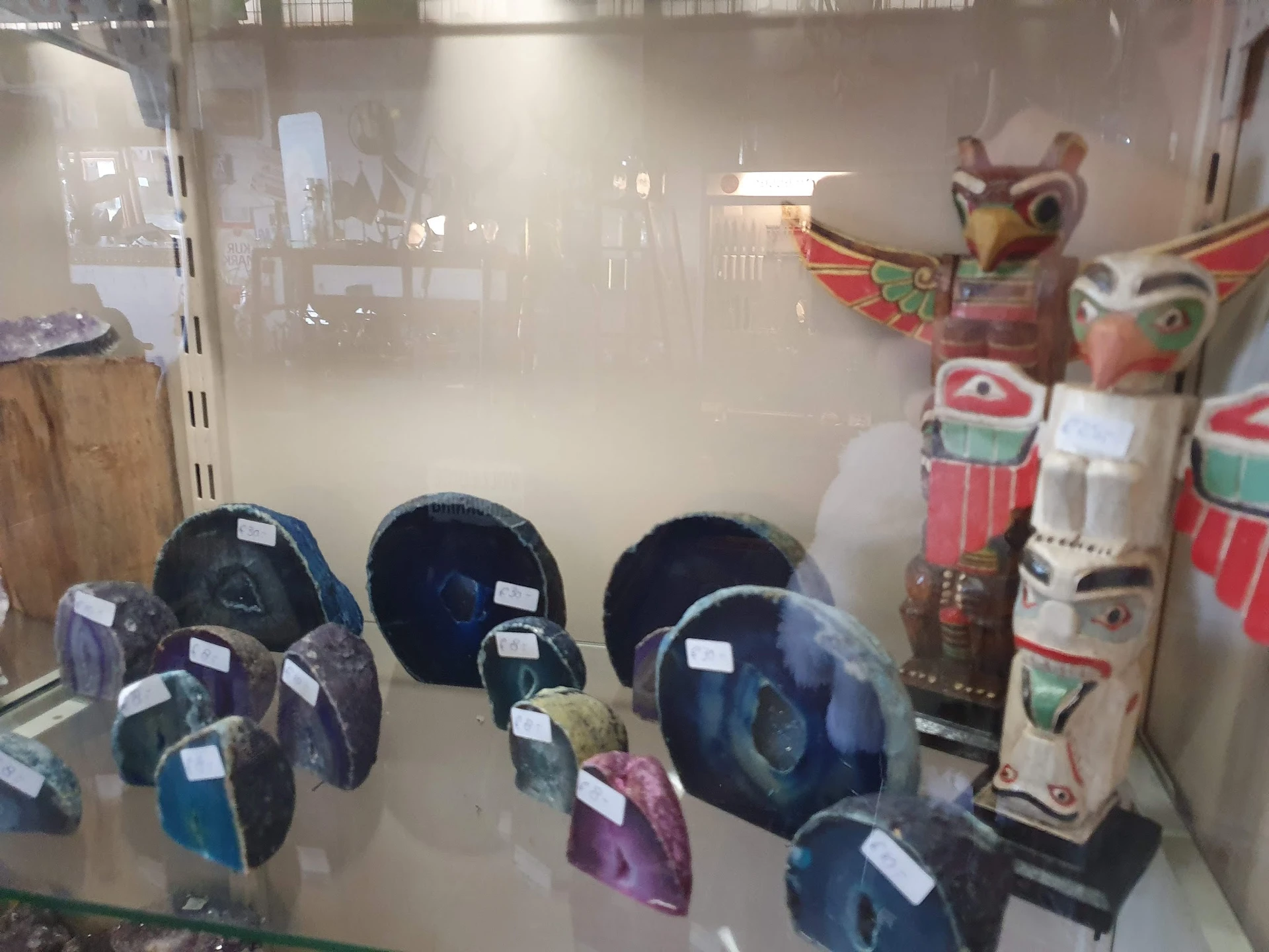 Glazen vitrinekast met verschillende blauwe helmen en decoratieve maskers op de achtergrond