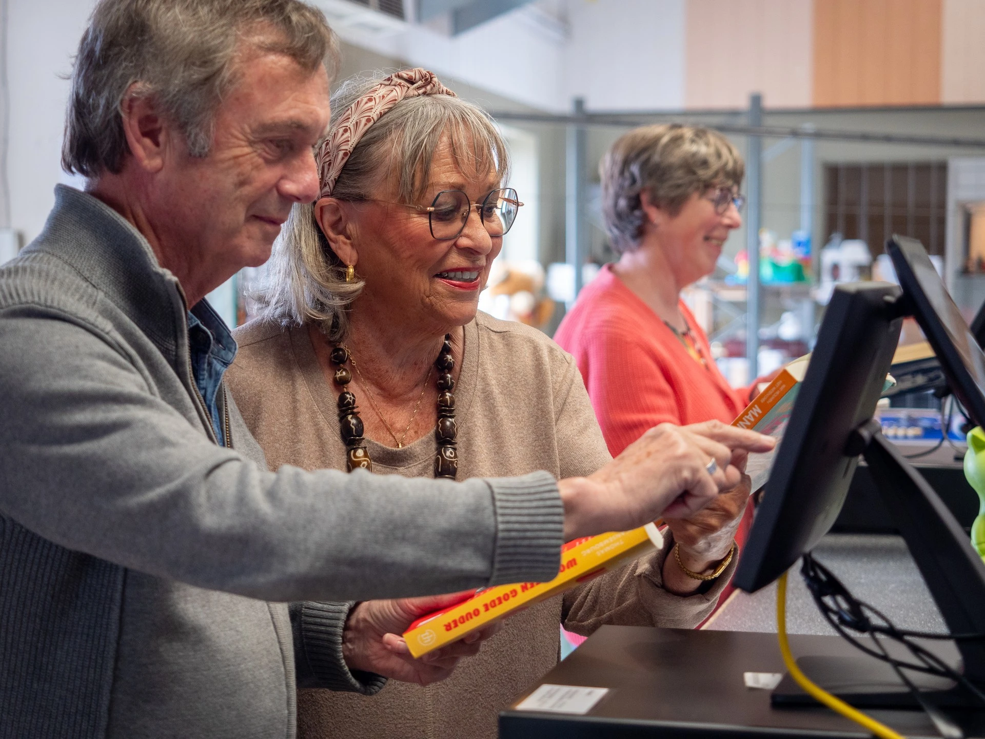 Medewerker helpt bezoeker bij het gebruik van een computer in de winkel