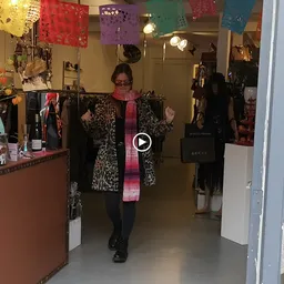 Binnenkant van kringloopwinkel met kledingrekken, decoraties en een bezoekers die kleding bekijkt