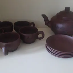 Bruin aardewerk servies: theepot, kopjes en schotels